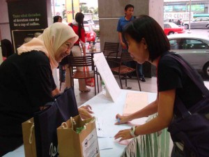 Supporter of Earth Hour Campaign registering. Welcome to Penang Earth Hour Countdown! Supporters being provided with a Cleome rutidosperma plant and goody bag while registering